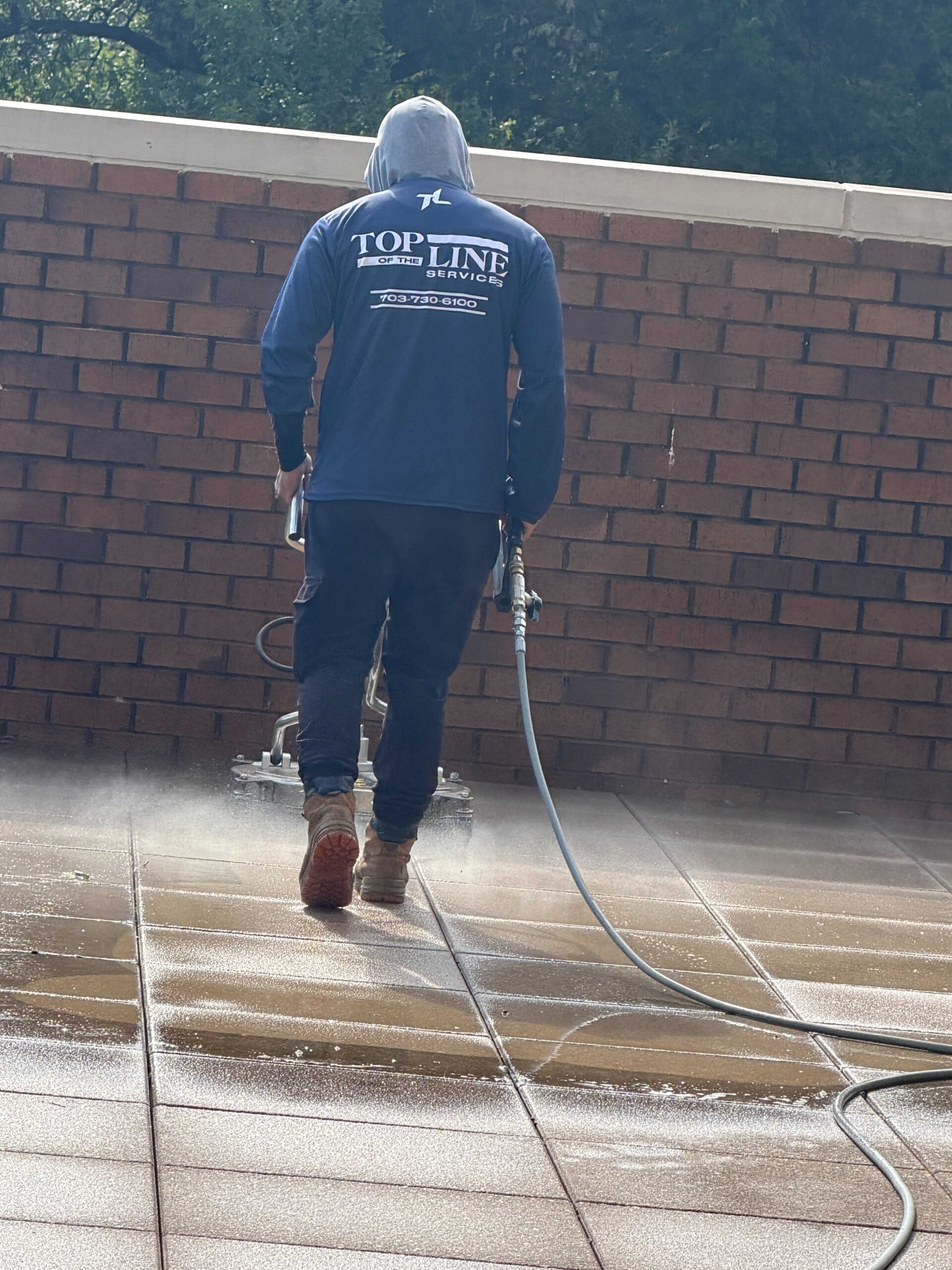 Technician pressure washing a concrete plaza at a commercial property