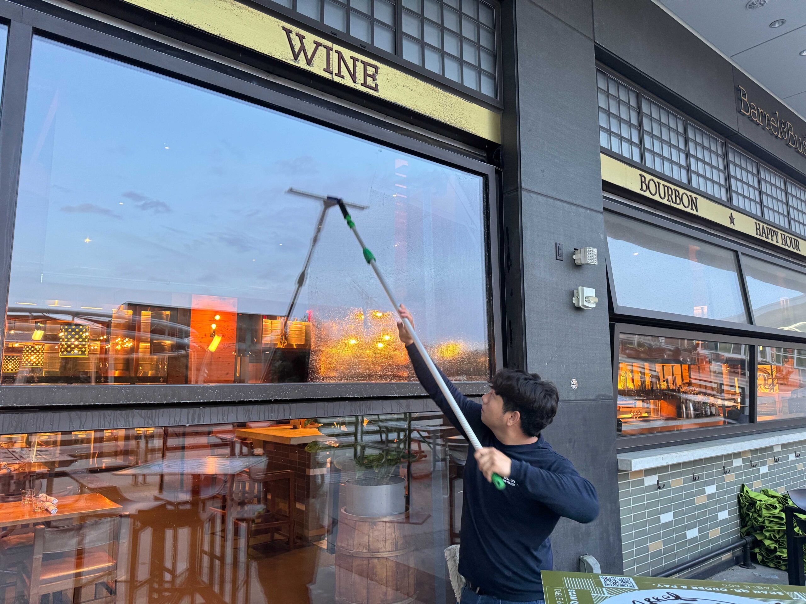 Technician cleaning storefront windows on a commercial retail building