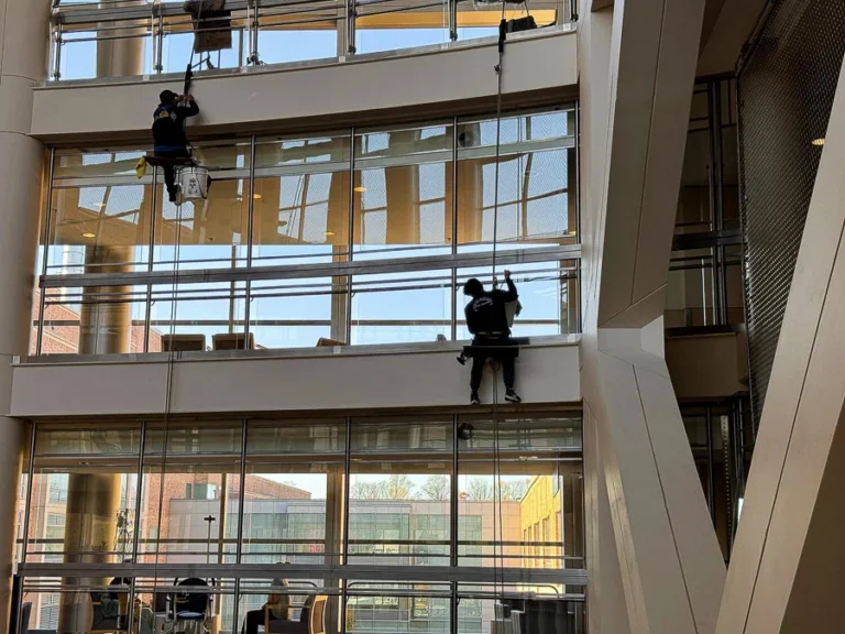 Wide view of technicians cleaning high interior windows in a commercial atrium