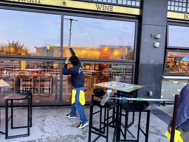 Technician cleaning windows beside a commercial restaurant patio