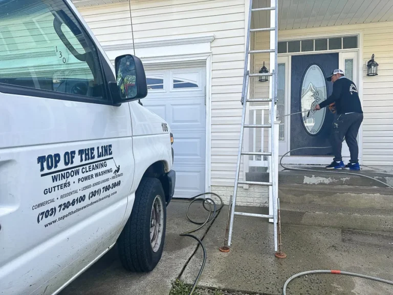 Technician cleaning front-entry glass beside a Top of the Line service van