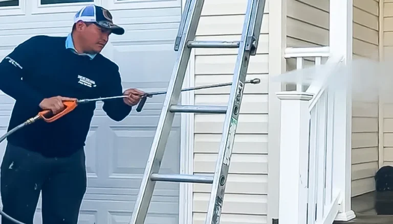 Top of the Line technician pressure washing the exterior siding of a home