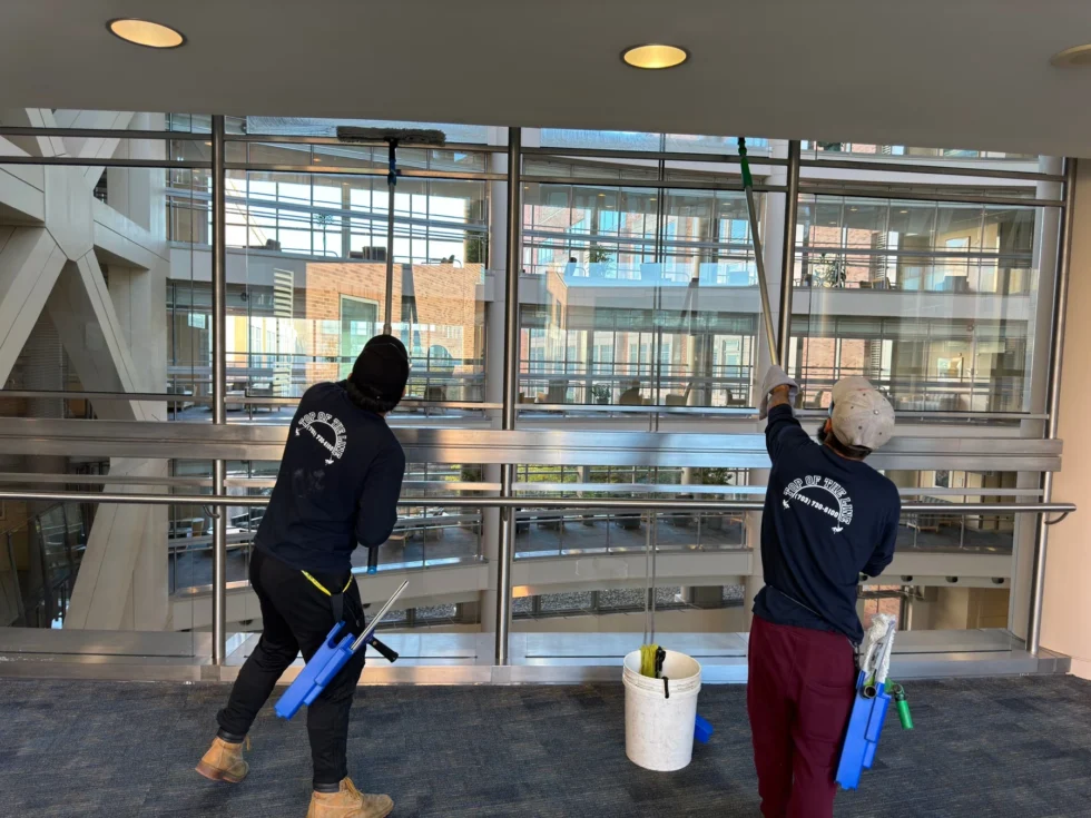 Two technicians cleaning glass inside a commercial lobby