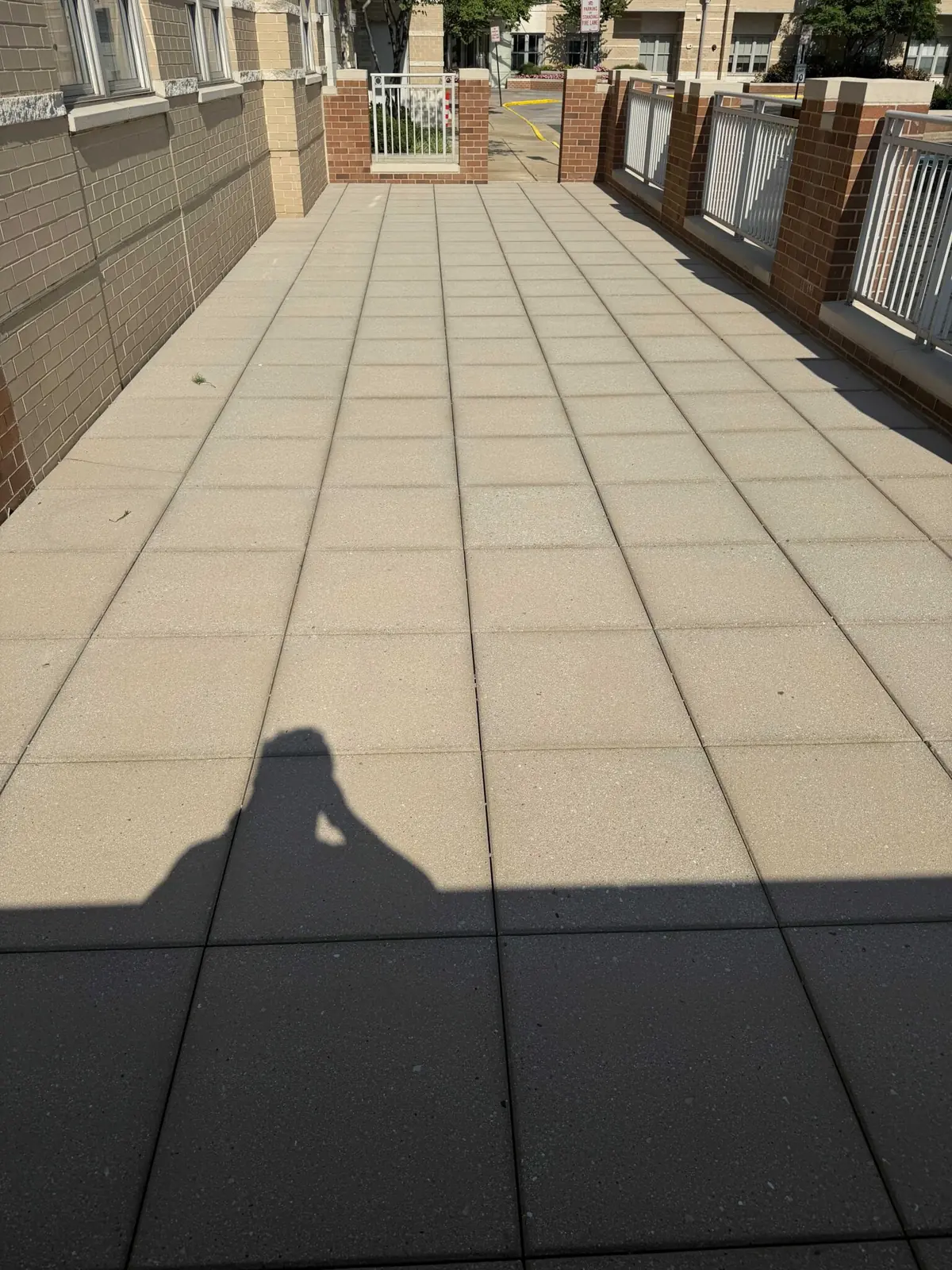 Paved walkway beside a brick building with white railings.