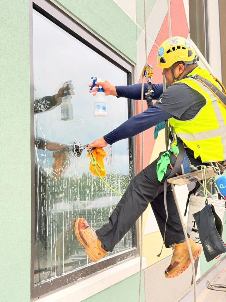 Rope-access technician cleaning a commercial window