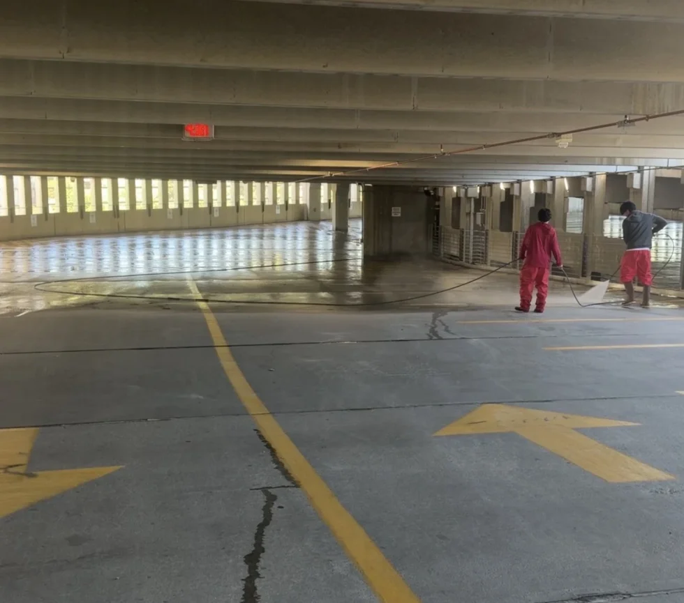 Technician pressure washing the floor of a parking garage