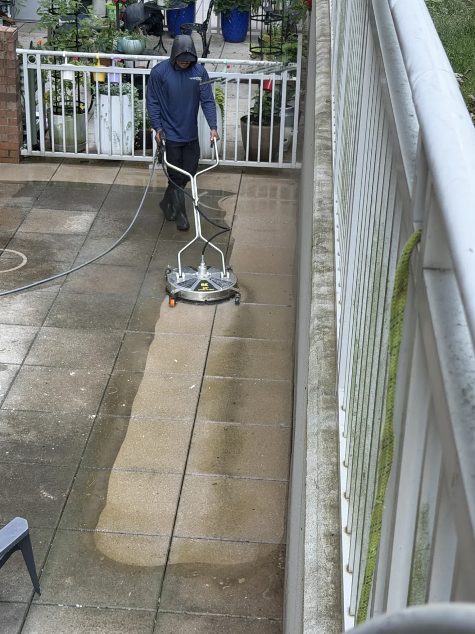 Technician using a surface cleaner on a stone patio