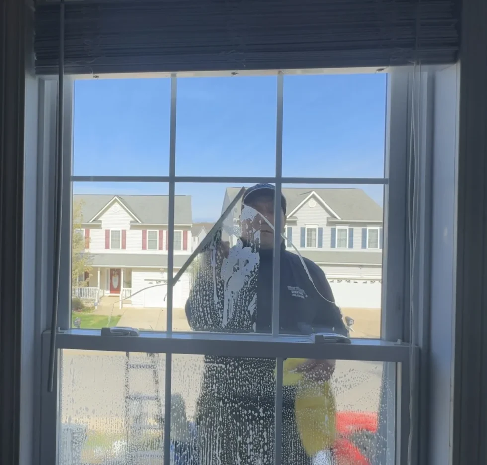 Window cleaning technician seen through a residential window